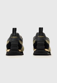 Vihreät ja mustat lenkkarit, joissa on teksturoitu päällinen, sileät nahkaelementit ja kevyt, uritettu musta pohja. Kultainen brändäys kantapäässä.