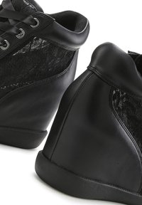 Schwarze High-Top-Sneaker aus einer Kombination von Leder und Schnürsenkeln, mit einem runden Keilabsatz und einer flachen Gummisohle.