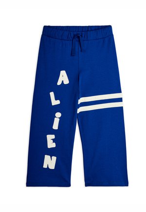 Pantalones azules de pierna ancha con cintura elástica y cordón, con letras blancas "ALIEN" verticales en la pierna izquierda y dos rayas blancas en la pierna derecha.