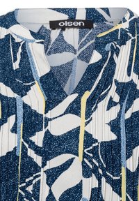 Navy and white blouse with abstract floral pattern, pleated texture, and V-neckline. Brand label "olsen" visible at the collar.