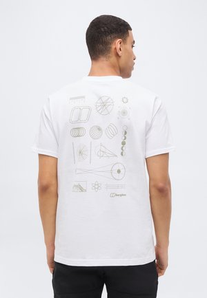 Vyras, stovintis nugara, dėvi baltą marškinėlį su mokslo ir geometrinėmis diagramomis, atspausdintomis šviesiai pilka spalva ant nugaros, prieš paprastą foną.