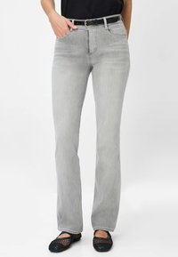 Grijze denim jeans met een rechte pasvorm, een medium taille, vijf zakken en een zwarte riem. G gedragen met zwarte mesh ballerina's.