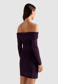 Μωβ φόρεμα με ανοικτούς ώμους και μακριά μανίκια, με ρυτιδωτές λεπτομέρειες στο σώμα και εφαρμοστή σιλουέτα. Απαλή υφή, μήκος πάνω από το γόνατο.