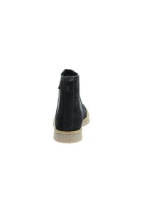 Botines de terciopelo negro con una superficie texturizada, que cuentan con una suela de color claro y un pequeño logo en la parte posterior, ofreciendo un diseño sencillo y estructurado.