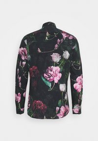 Langärmliges Hemd mit schwarzem Hintergrund, versehen mit einem floralen Muster aus pinken und weißen Pfingstrosen, Rosen und grünen Blättern. Mit Knopfmanschetten.