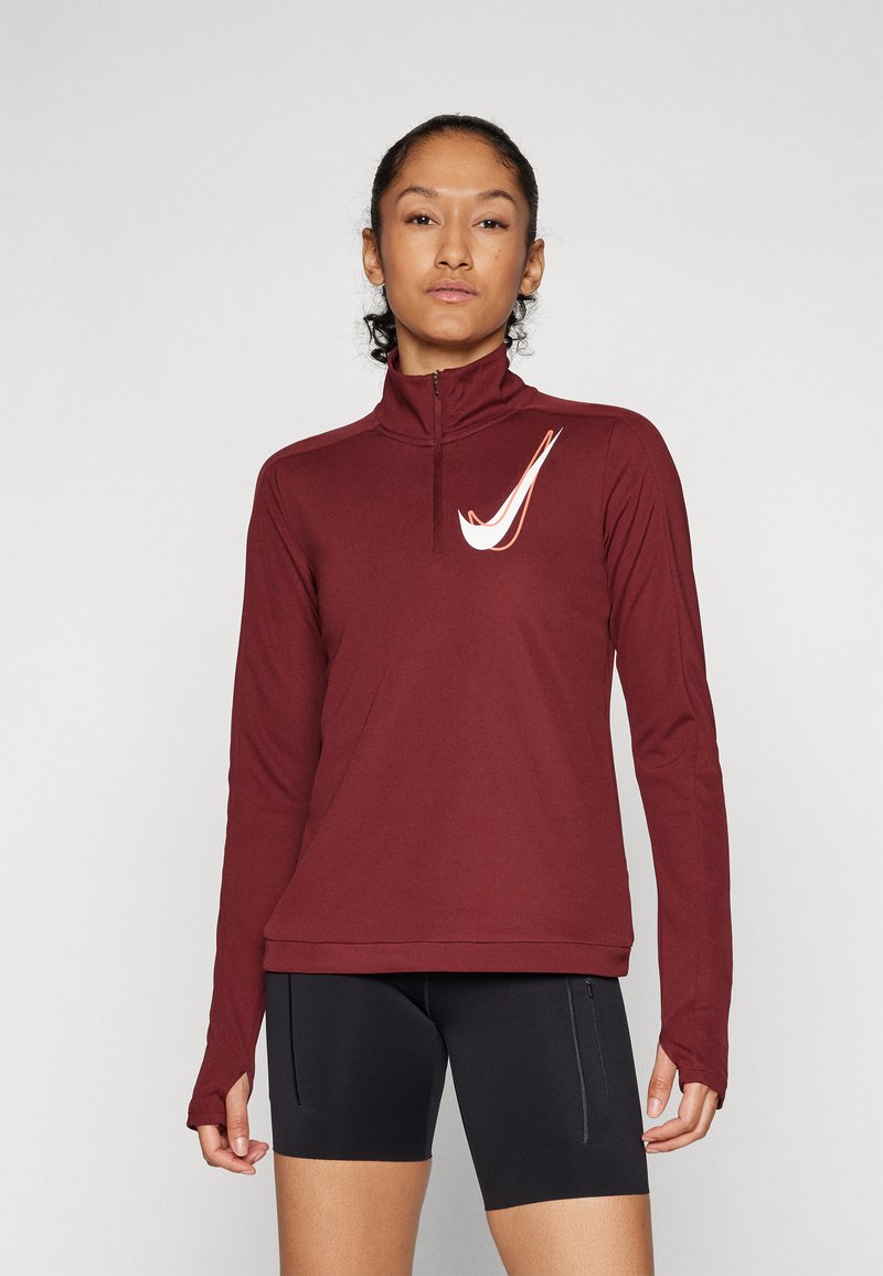 Maroon duguljasti sportski gornji dio dugih rukava s visokim ovratnikom i četvrtim patentnim zatvaračem. Ima bijeli Nike logo na prsima. Glatka tkanina s prilagođenim dizajnom.