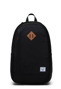 Mochila negra hecha de un tejido duradero, con un parche de diamante de cuero marrón texturizado y una etiqueta de logo blanca en la parte inferior.