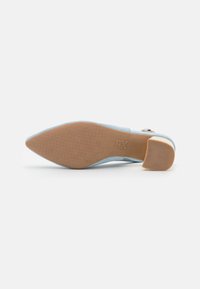 Chaussure slingback en daim bleu clair avec un bout pointu, dotée d'une semelle extérieure en caoutchouc beige et d'un petit talon. Motif de grip texturé sur la semelle.