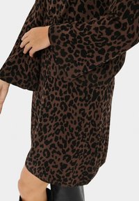 Vestido de punto marrón con estampado de leopardo negro, mangas largas acampanadas y textura acanalada, con un dobladillo que llega a medio muslo.