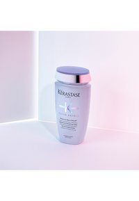 Kérastase Blond Absolu Bain Ultra-Violet violette Shampoo-Flasche für aufgehelltes, kühles blondes oder graues Haar auf weißer Oberfläche mit weichem Licht.