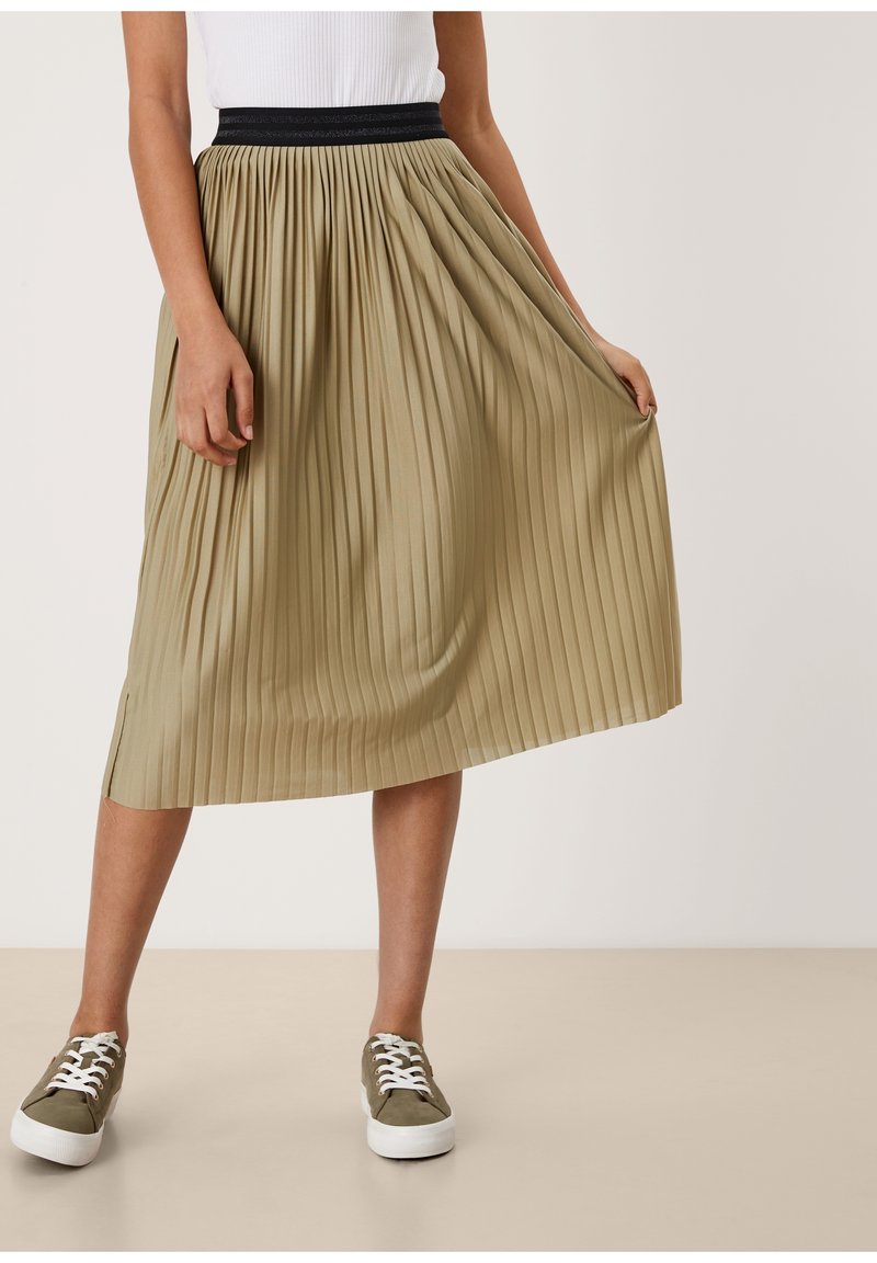 Knee-length plisserad kjol i ljus khaki med svart elastisk midja, som har en slät finish och sidoflikdetalj. Bärs med sneakers.