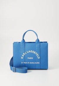 Niebieska torba płócienna z dwiema krótkimi rączkami i odczepianym paskiem na ramię. Może poszczycić się białym napisem "KARL LAGERFELD PARIS" oraz adresem.