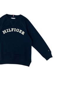 Felpa blu navy realizzata in misto cotone, con la scritta "HILFIGER" ricamata in crema. Maniche e girovita a costine con dettagli logo laterali.