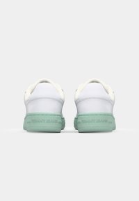 Baskets blanches avec une semelle en caoutchouc verte, dotées d'un dessus en cuir lisse et d'une branding subtil au talon. Design classique avec un profil bas.