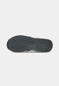 Sneaker with a textured black rubber sole, multi-colored upper composed of various materials, and reinforced toe cap.