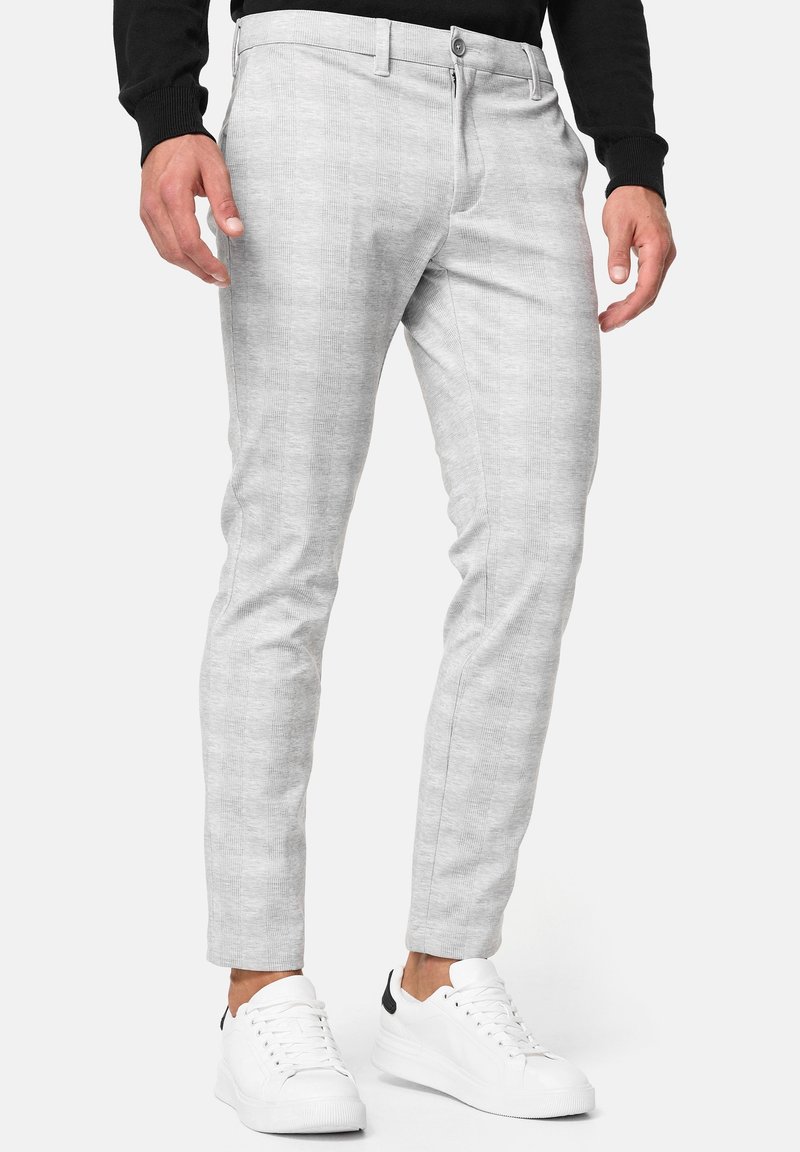 Light gray slim-fit men's pants made of soft fabric, featuring a subtle textured pattern, button closure, and side pockets, paired with white sneakers.