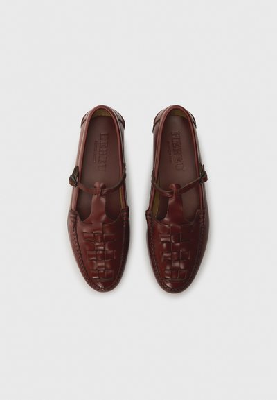 Red leather shoes with a woven design, rounded toe, and side straps. Smooth texture with contrasting stitching along the edges.