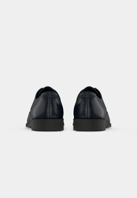 Pair of black leather dress shoes shown from the back on a plain white background.
