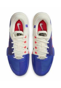 Sneaker con una combinazione di colori bianco, blu e rosso, caratterizzate da una tomaia in mesh e sintetico, suola testurizzata e il logo Nike distintivo.