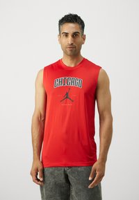Piros ujjatlan sportpóló, amelyen a "CHICAGO" felirat és egy fekete jumpman logo található az elején; sima, könnyű anyagból készült.
