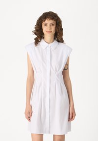 Λευκό, κοντομάνικο φόρεμα-πουκάμισο με γιακά, κλείσιμο με κουμπιά μπροστά και πλαϊνές πιέτες, φτιαγμένο από απαλό ύφασμα.