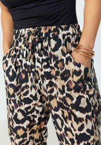 Luipaardprint broek met een elastische tailleband en trekkoord. Gemaakt van een gladde stof met zijzakken en voorzien van bronzen hardware-accenten.