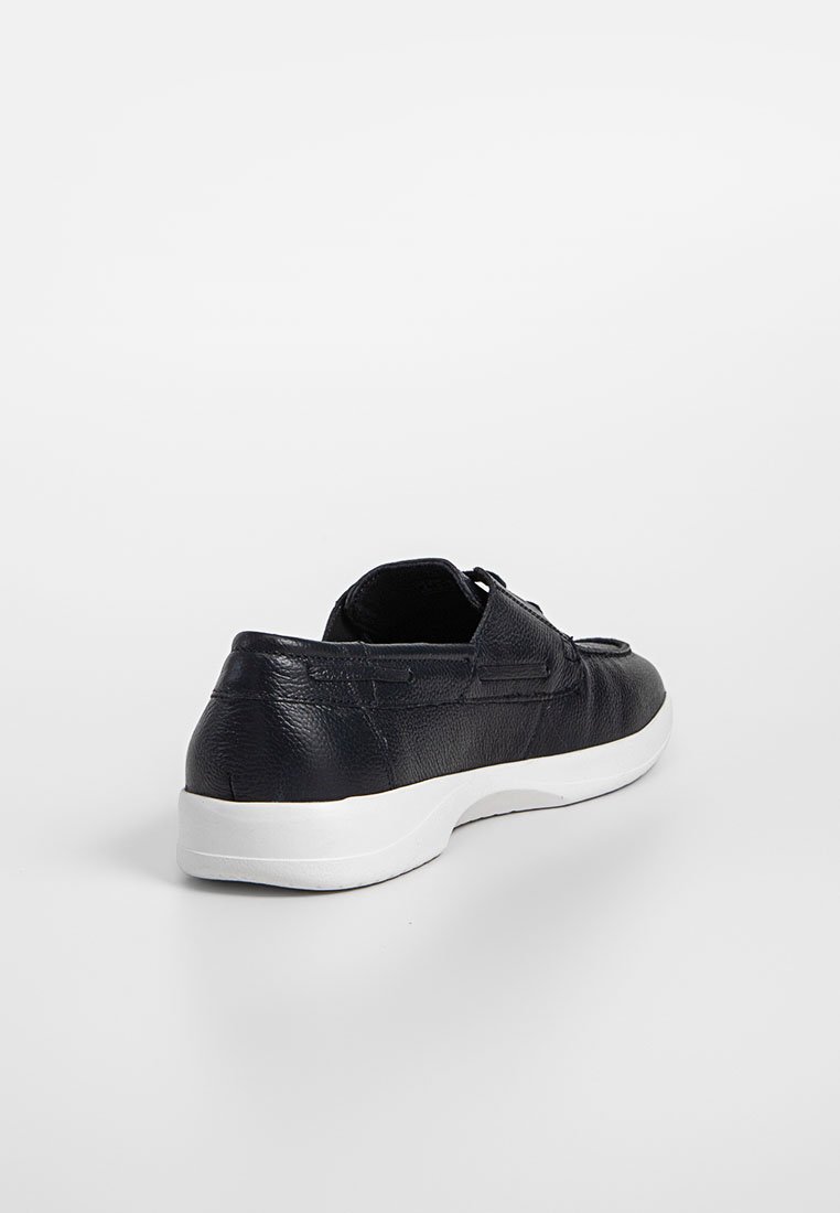 Baskets en cuir noir avec une finition texturée, semelle en caoutchouc blanc et détails de laçage, présentant un bout rond et un col rembourré.