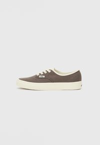 Brune kanvas sneakers med lavt snitt, hvite lisser og gummisåler. Har et lite logo-patch på siden og kontrasterende hvite detaljer.