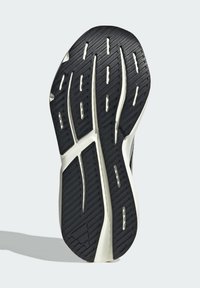 Čierna gumená podrážka obuvi s textúrovanými gripovými vzormi, bielymi akcentmi a jasne definovaným dezénom.