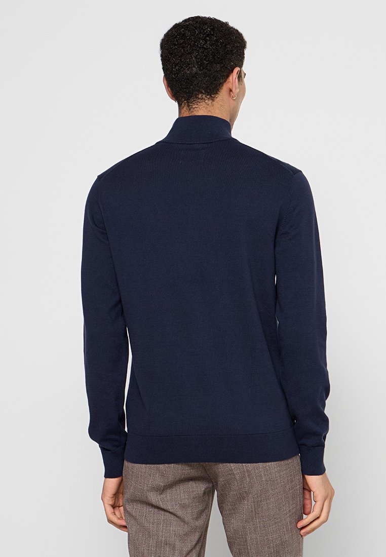 Granatowy sweter z dzianiny z kołnierzem, długimi rękawami, ściągaczami przy mankietach i u dołu. Gładka faktura i dopasowany krój.