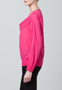 Ljusrosa långärmad blus med en avslappnad passform, med samling vid handlederna och fållen. Lättvikts tyg med en mjuk textur, som har en rund halsringning.
