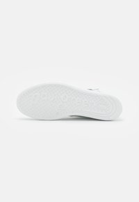 White sneaker sole with textured grip, featuring rounded edges and "Paul Green" embossed for brand identification. Flat and smooth surface.