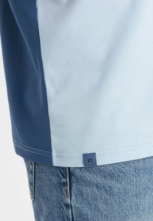 Kurzarmhemd mit einem Farbblockdesign in Hellblau und Dunkelblau. Weiches Baumwollmaterial, mit einem kleinen Logoschild am Saum.