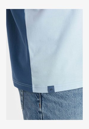 Camicetta a maniche corte con un design a blocchi di colore in azzurro chiaro e blu scuro. Realizzata in morbido cotone, presenta un piccolo logo etichetta all'orlo.