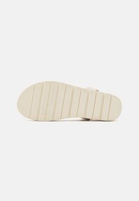 Sandal såle i beige gummi, med et rillemønster for bedre grep. Designet har en glatt finish og diskret merkevaredetalj.