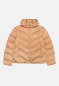 Veste rembourrée beige avec capuche. Design matelassé en chevrons, fermeture éclair à l'avant et poches latérales. Comprend le logo blanc de Nike sur la poitrine.