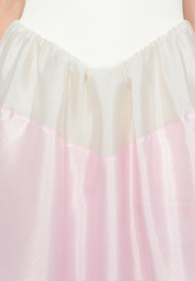 Lagdelte nederdele med en gennemsigtig hvid top med en samlet talje og en pastelfarvet rosa nederste del. Tekstureret, let stof.