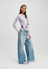 Ελαφρύ, παστέλ tie-dye μπλουζάκι μακρύ μανίκι σε συνδυασμό με oversized ανοιχτό μπλε τζιν. Αξεσουάρ περιλαμβάνουν μια μικρή ανοιχτό μωβ τσάντα χιαστί.