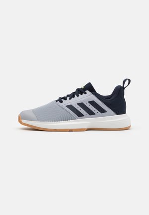 Scarpa da ginnastica atletica in grigio chiaro e blu navy con suola in gomma color miele, strisce nere sul lato, lacci neri e linguetta sul retro del tallone.