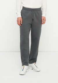 Pantalones de chándal grises hechos de una suave mezcla de algodón, con una cinturilla elástica con cordón y bolsillos en las costuras laterales.