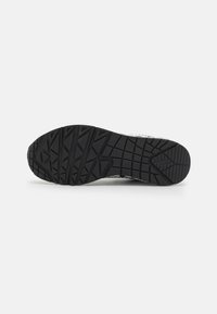 Black rubber shoe sole with textured tread pattern for grip. Features pronounced grooves and rounded toe for stability.