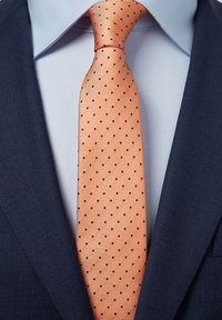 Marinblå kavaj i texturerat tyg, ljusblå skjorta och ett orange slips med svarta prickar.