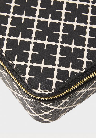 Black and white patterned cosmetic bag with a textured finish, gold zipper, and supportive shape with distinct geometric designs.