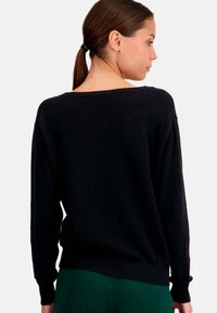 Pull en tricot noir avec une coupe décontractée, un large col et des manches longues. Présente un ourlet côtelé et une texture douce. Convient pour un usage décontracté.