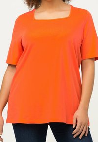 Camiseta de manga corta de color naranja brillante con escote cuadrado, hecha de una tela suave, que presenta un diseño de corte holgado.