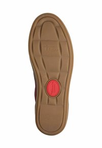 Suola di una scarpa, realizzata in materiale gommoso con una superficie marrone strutturata, motivi rettangolari e un pulsante di comfort rosso circolare.