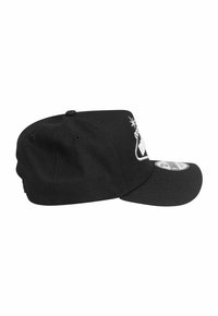 Casquette noire avec une visière plate et un dos légèrement arrondi. Elle présente un motif brodé blanc et une patch logo sur le côté. Fabriquée en tissu texturé.