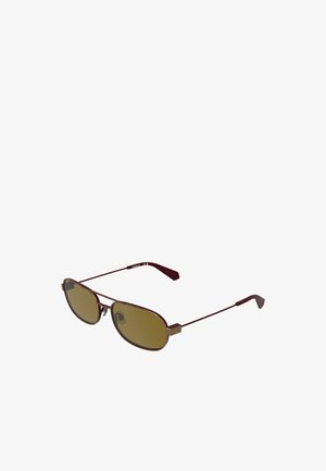 Brązowe owalne okulary przeciwsłoneczne z cienką metalową oprawką i noskami, smukłe zauszniki z plastikowymi końcówkami, pokazane pod kątem z boku.