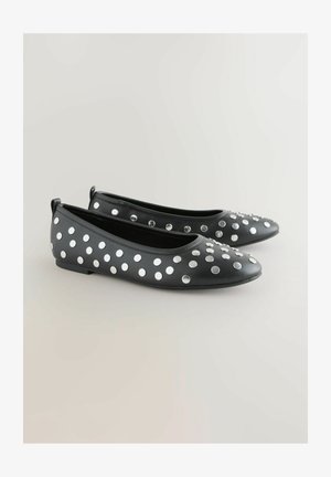 Schwarze Ballerinas mit glatter Textur und großen silbernen Nieten in Tupfenmuster auf dem Obermaterial. Flaches Design mit Fersenlaschen.