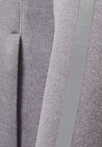 Lila Stoff mit einer strukturierten Oberfläche, die an einer Seite einen glatten grauen Streifen aufweist. Das Design legt den Fokus auf Einfachheit und Funktionalität.
